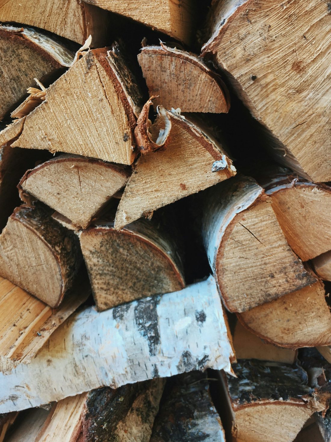 A stack of split birch logs, bark and pale wood facing out.