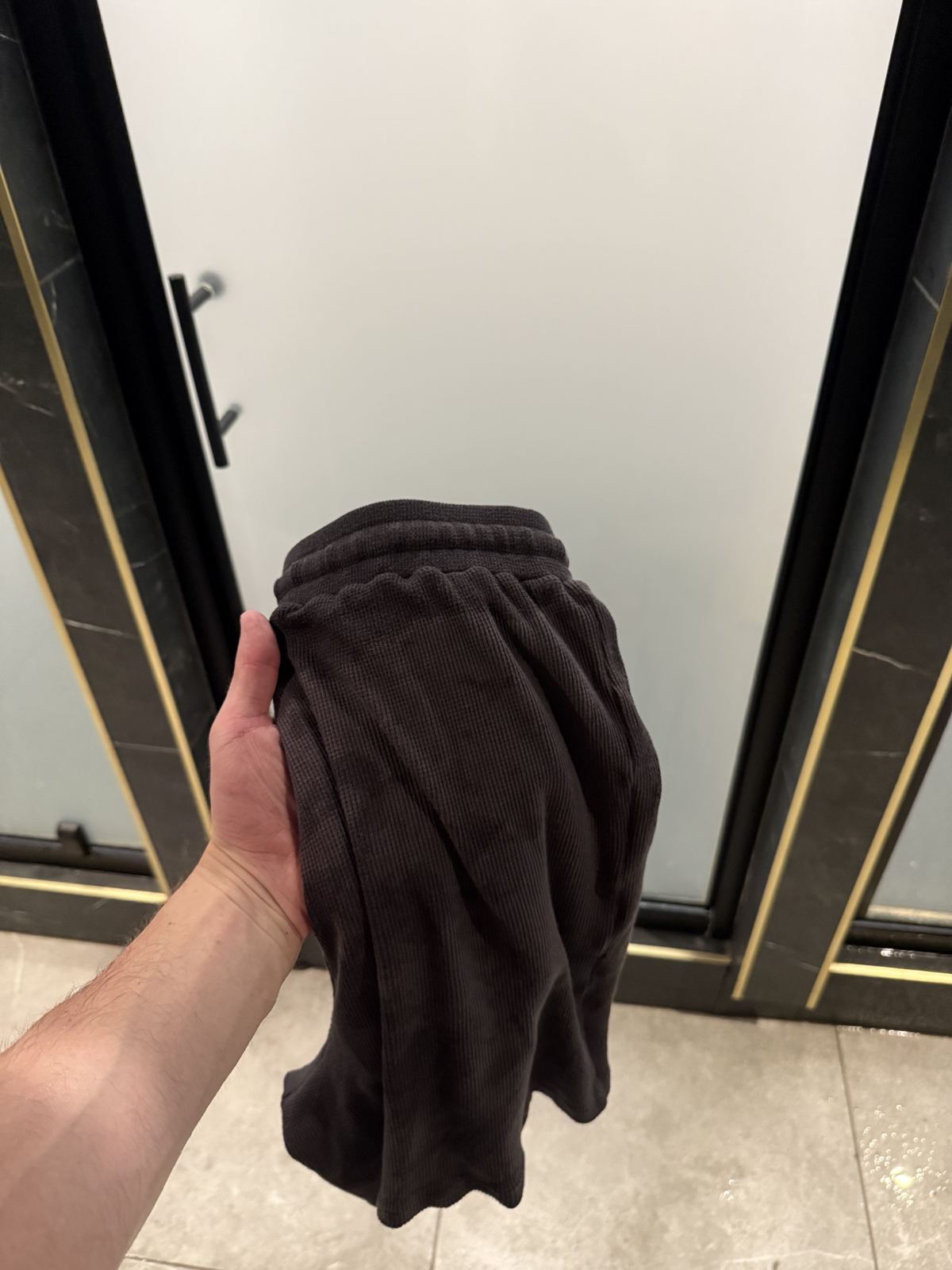 A hand holding up the Amuro short, the waffle knit texture of the shell visible.