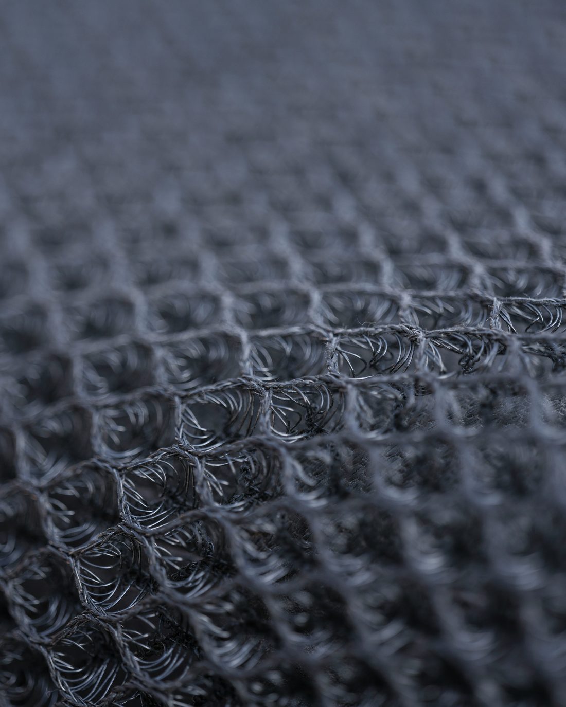 Close-up of a dark charcoal waffle-knit fabric, showing the raised cell structure.